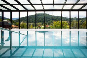 A swimming pool with a view of a mountainous landscape through large windows. - Hotel Beskid Balneo Medical Resort & SPA (Piwniczna-Zdroj)