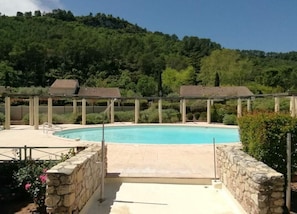 A swimming pool with stone walls and a pergola structure.