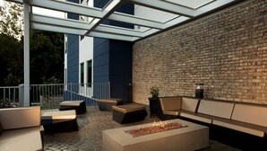 An outdoor patio with a fire feature, seating, and a brick wall. - SpringHill Suites Chester (Chester)