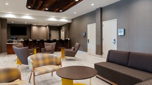 A modern lobby with seating areas, a reception desk, and a television screen. - SpringHill Suites Chester (Chester)