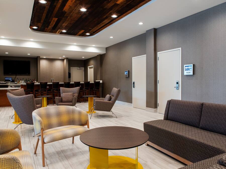 A modern lobby with seating areas, a reception desk, and a television screen.