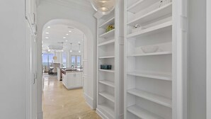 A modern kitchen with white cabinetry, a central island, and a dining area with a view. - Kings View|Private Beach Access|Gulf Front Home with Stunning Gulf Views (Destin)
