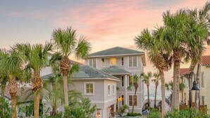 A two-story building with a courtyard, surrounded by palm trees and a cobblestone path. - Kings View|Private Beach Access|Gulf Front Home with Stunning Gulf Views (Destin)