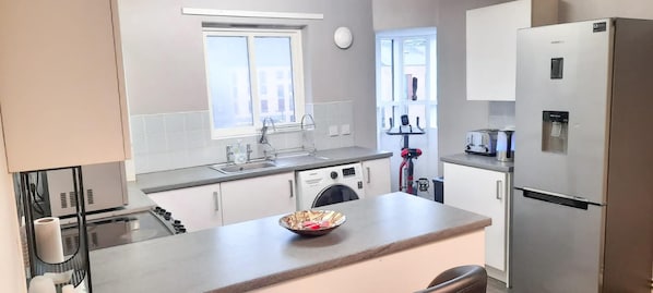 Enjoy cooking in this well-equipped kitchen with a stainless steel refrigerator, oven, and sink with a window.