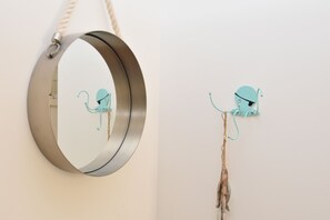 A circular mirror with a rope handle and a wall-mounted hook with a decorative item.