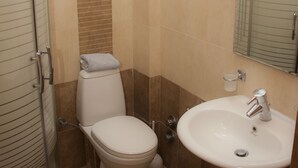 Un baño con ducha, inodoro, lavabo y toallero.