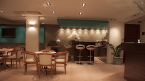 Un restaurante con sillas y mesa de madera, una barra con una planta y una pared color aguamarina.