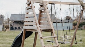 A wooden swing set with a slide and a ladder in a grassy yard. - Stone farmhouse for 6 people with heated swimming pool (Trélévern)