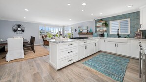 Una cocina moderna con armarios blancos, una isla central y vistas al exterior.
