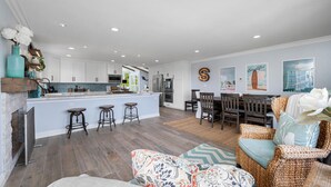 Una cocina amplia con una isla central, taburetes de bar y una zona de comedor con una mesa y sillas de madera.