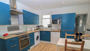 A modern kitchen with blue cabinets, stainless steel appliances, and a wooden dining table. - Still Waters (Swanage)