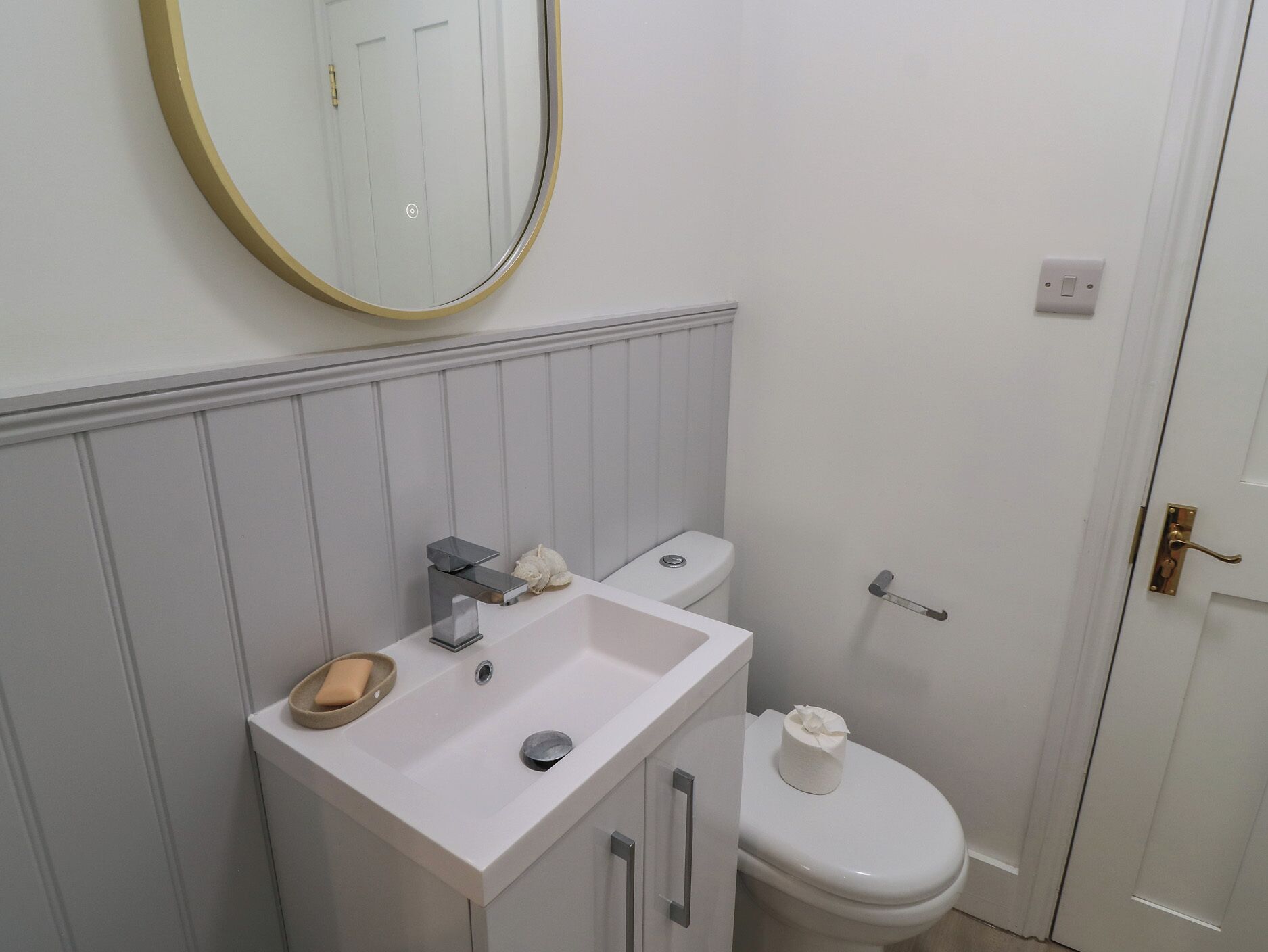 A bathroom with a white sink, a toilet, and a mirror with a gold frame.