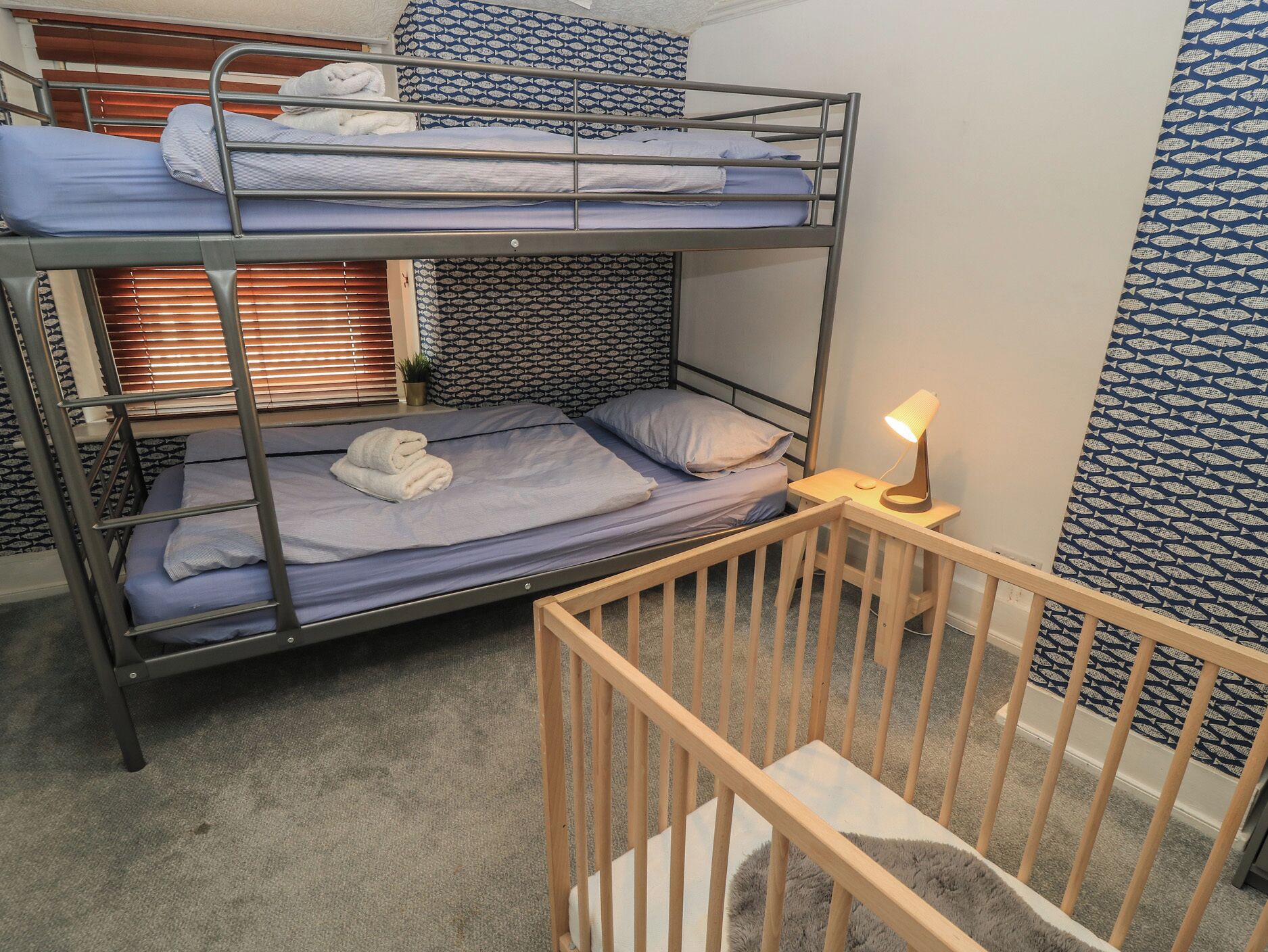 A bunk bed room with a small desk and a lamp.