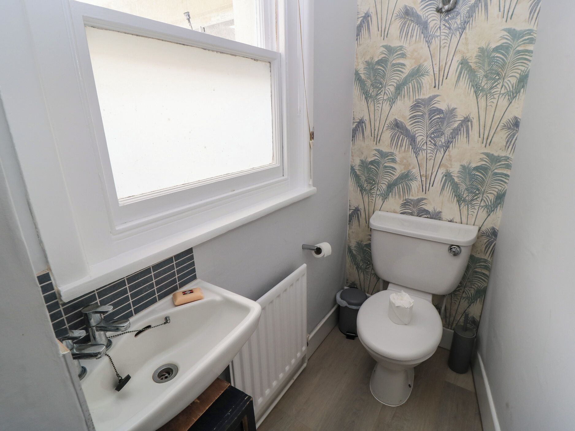 A small bathroom with a white sink, a toilet, and a window.