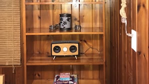 Uma estante de madeira com um enfeite de casa, um pequeno alto-falante e alguns livros.