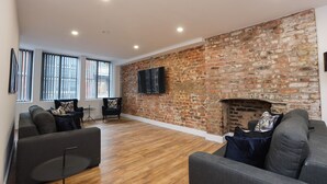 A spacious living room with a brick wall, a fireplace, and modern furniture. - Wood Street Apartments (Liverpool)