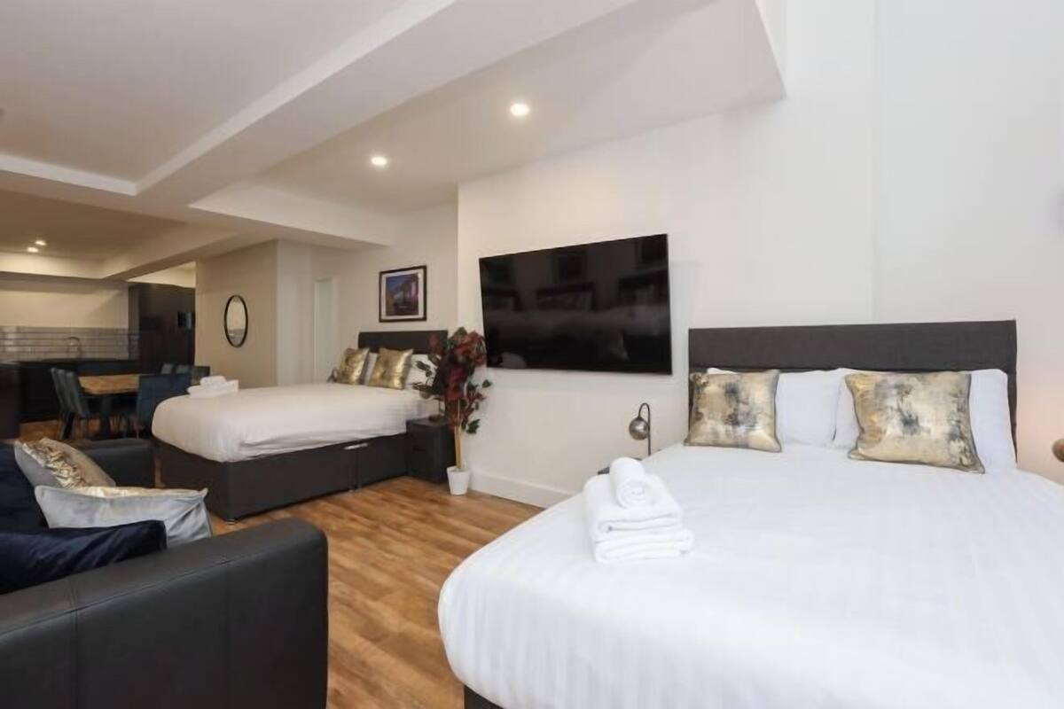Una habitación de hotel con una cama grande, un sofá, un escritorio y una televisión.
