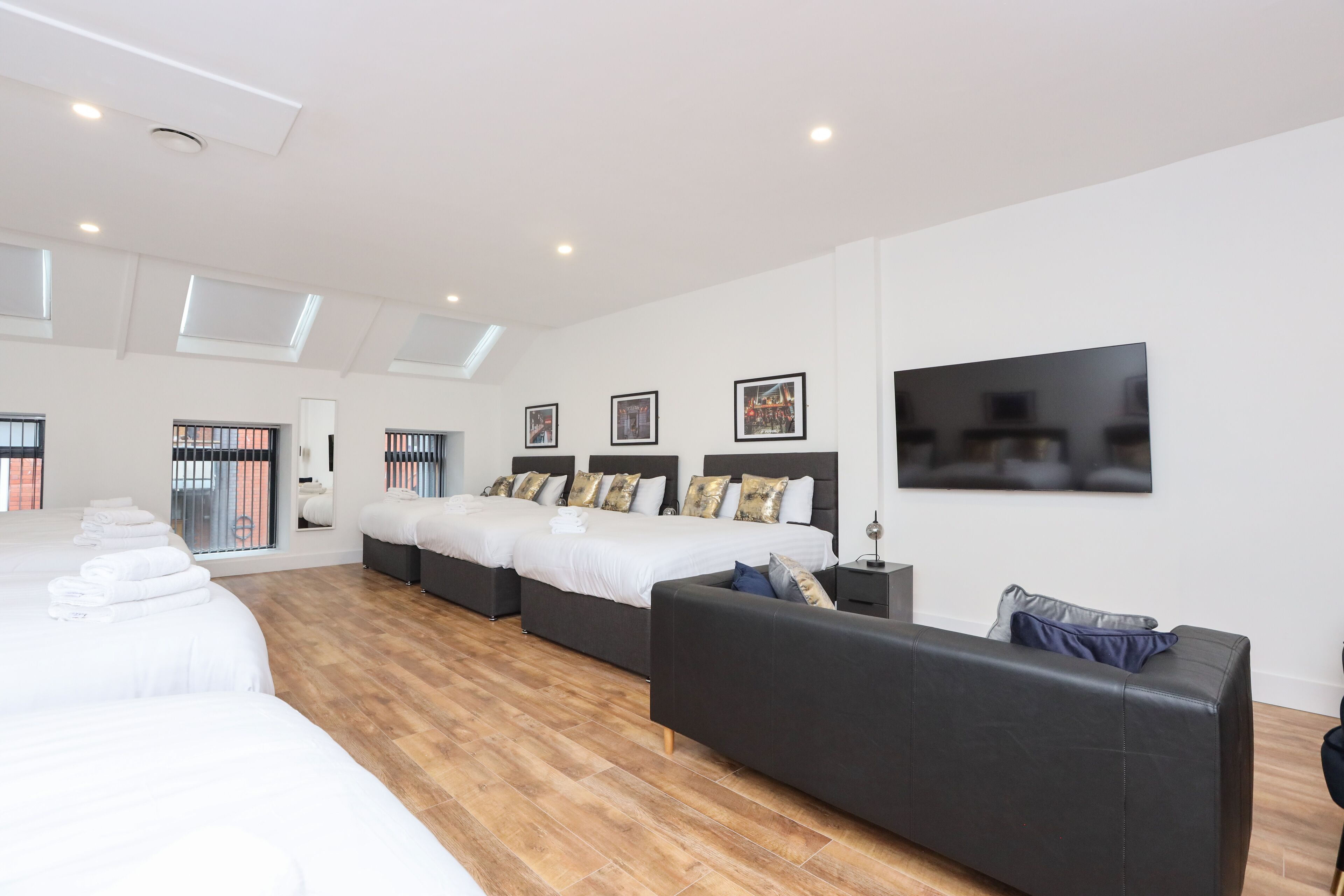 A modern hotel room with a large bed, a sofa, and a flat-screen TV.
