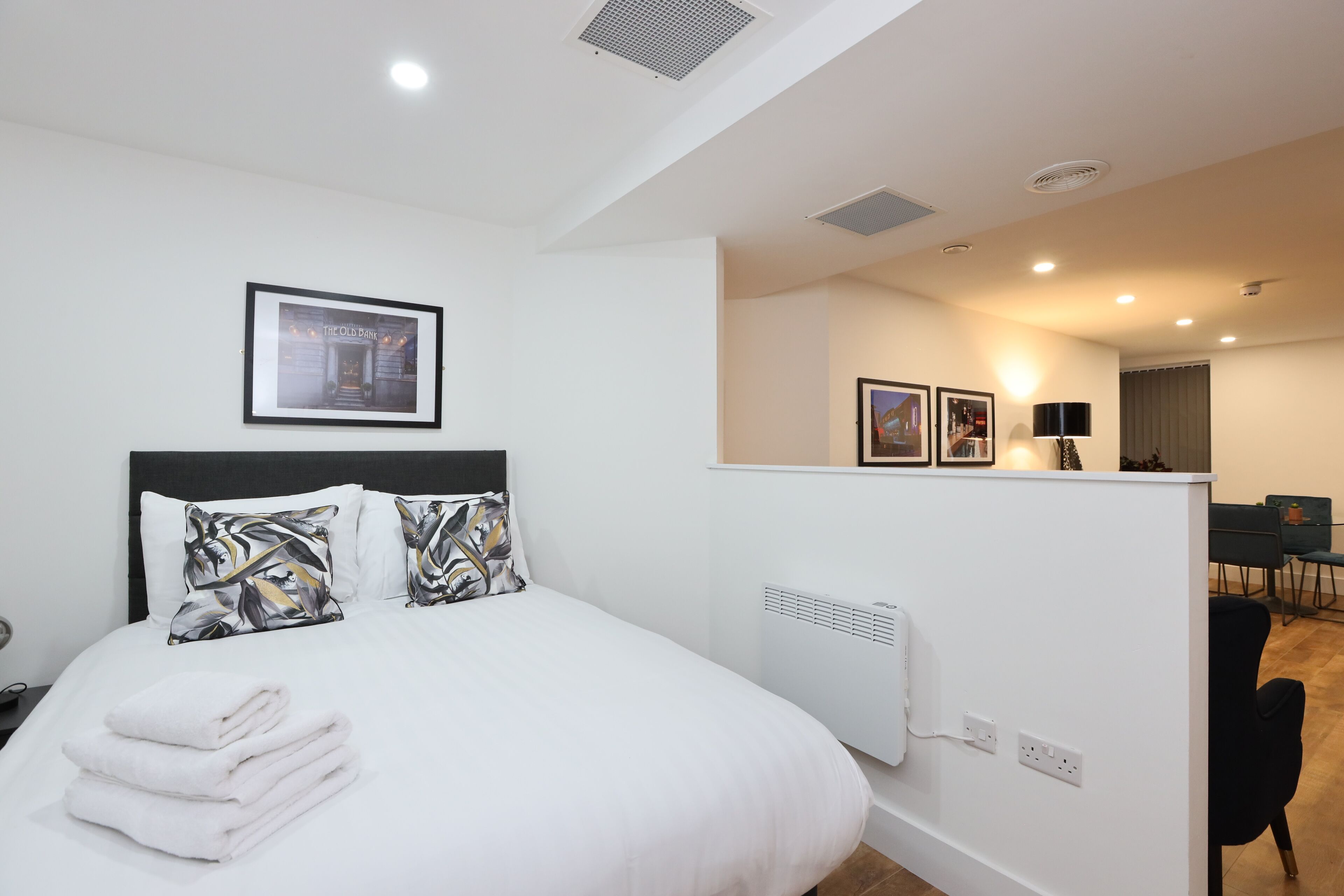 Una habitación de hotel moderna con una cama bien hecha, una kitchenette pequeña y un comedor.