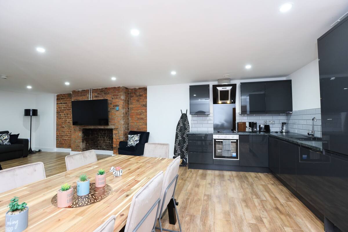 Una cocina moderna con armarios oscuros, un horno empotrado y un televisor de pantalla plana montado sobre la encimera.