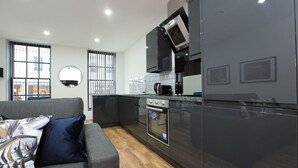 A modern kitchen with dark cabinetry, a built-in oven, and a microwave. - Wood Street Apartments (Liverpool)
