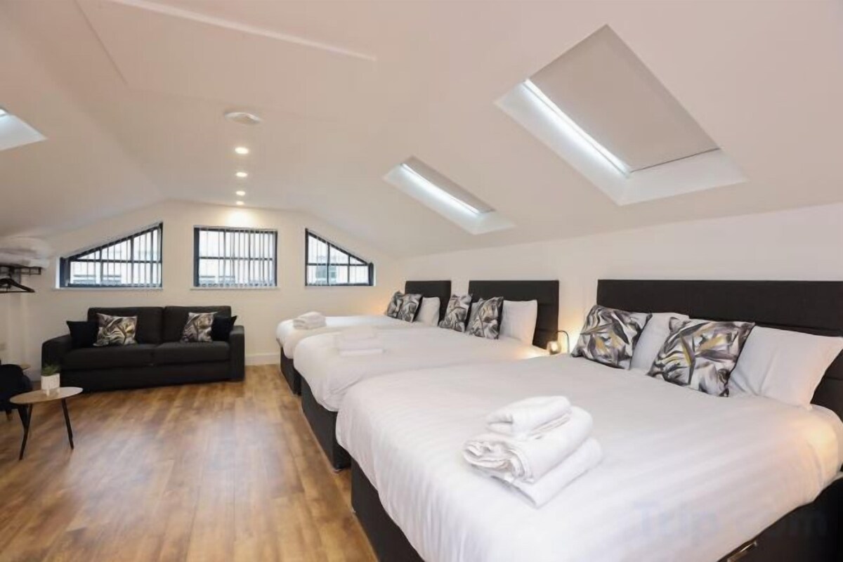 A bedroom with a skylight, a sofa, and a large bed with pillows.