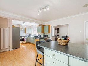A modern kitchen with a central island, bar stools, and a dining area. - 5 bedroom accommodation in Skegness (Skegness)