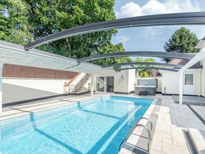 A swimming pool with a glass enclosure, a covered patio area, and a view of a residential building in the background. - 5 bedroom accommodation in Skegness (Skegness)