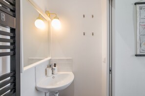 A bathroom with a white sink, two wall-mounted lights, and a framed map on the wall.