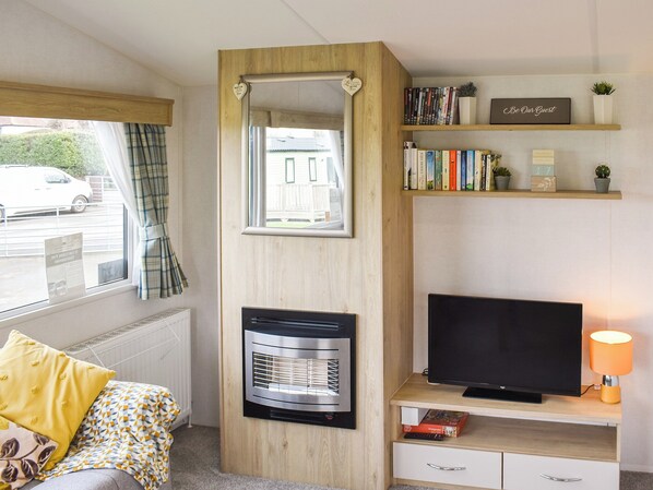 Une chambre avec un lit, une télévision, un radiateur, une bibliothèque et une fenêtre avec des rideaux.