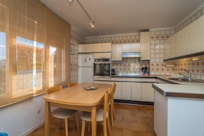 A compact kitchen with a dining table, built-in oven, and a sink.