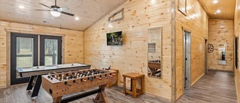 Relax in this inviting room with a foosball table, dining area, and ceiling fan for a comfortable stay.