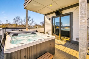 Un jacuzzi en una terraza de madera con un cerramiento de vidrio que da a un balcón.