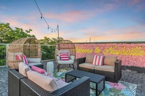 Un área de estar al aire libre con mobiliario de mimbre y un fondo de pared floral.