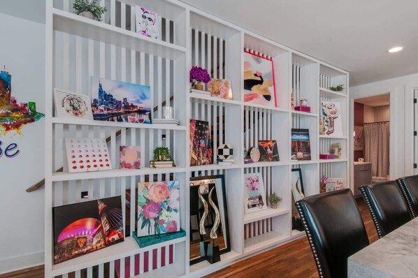 Un interior moderno con una estantería blanca que exhibe varios objetos decorativos y obras de arte.