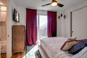Una camera da letto con un letto, un armadio in legno, una televisione e una finestra con tende.