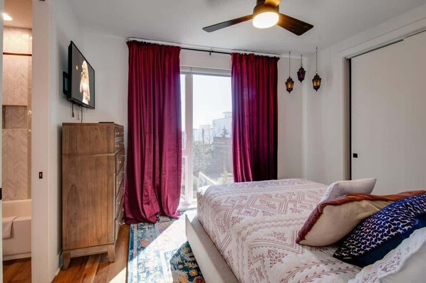 Un dormitorio con una cama, un armario de madera, un televisor y una ventana con cortinas.