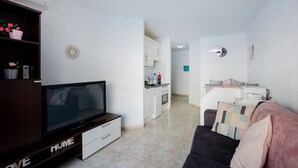 A modern living room with a flat-screen TV, a sofa, and a kitchen in the background. - Great location!1 bedroom Costa adeje very central (Costa Adeje)