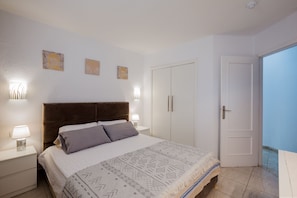 Un dormitorio con cama, lámparas de noche, armario y una puerta que da a un balcón.