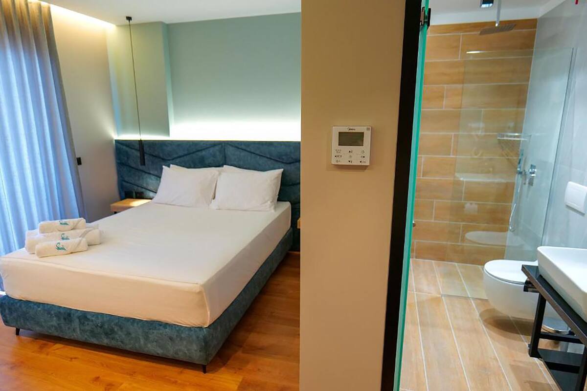 A hotel room with a bed, a control panel, a bathroom with a shower, and a toilet.