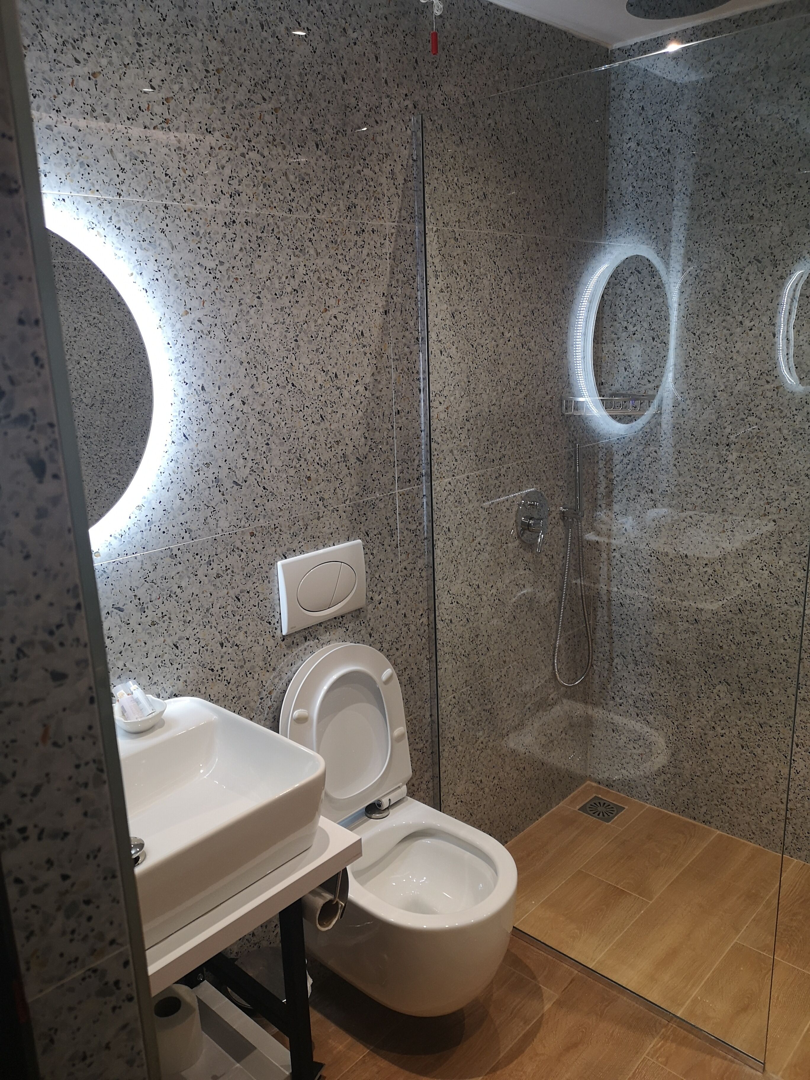 A modern bathroom with a freestanding toilet, a sink, and a glass-enclosed shower.