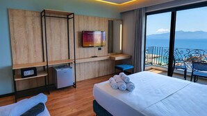 A hotel room with a bed, a TV, a desk, and a balcony with a view of the sea. - Seawave Hotel (Sarandë)