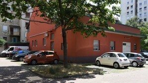 A parking lot with several cars parked in front of a building with a red and grey facade. - Mary's Apartment (Zagreb)