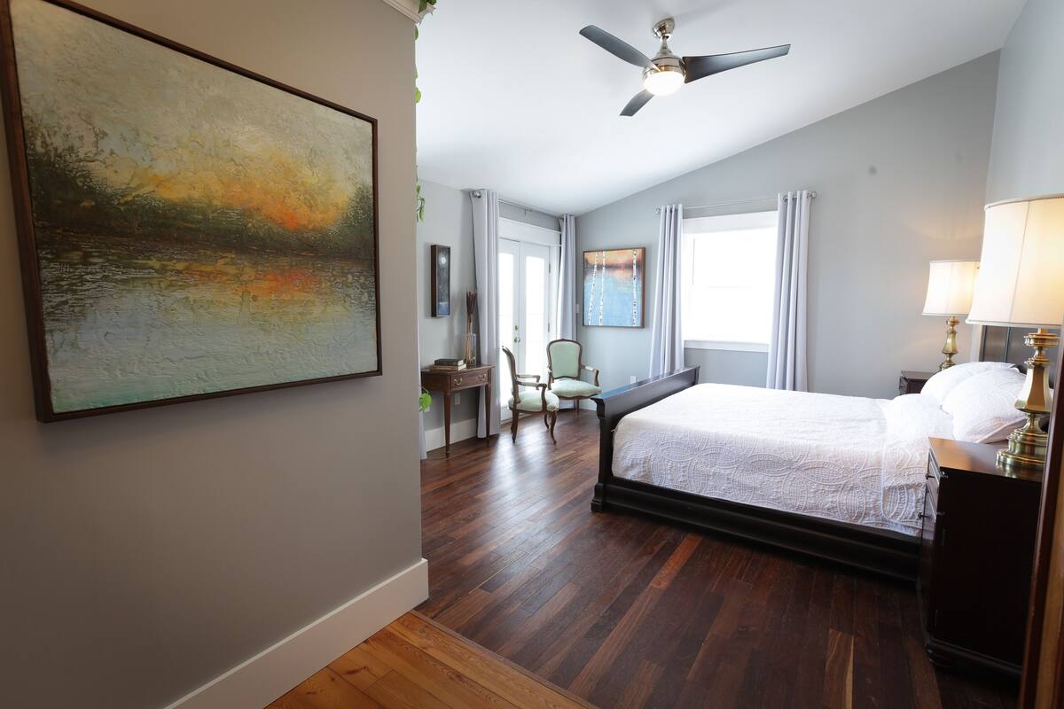A bedroom with a bed, a ceiling fan, a desk, and a chair.