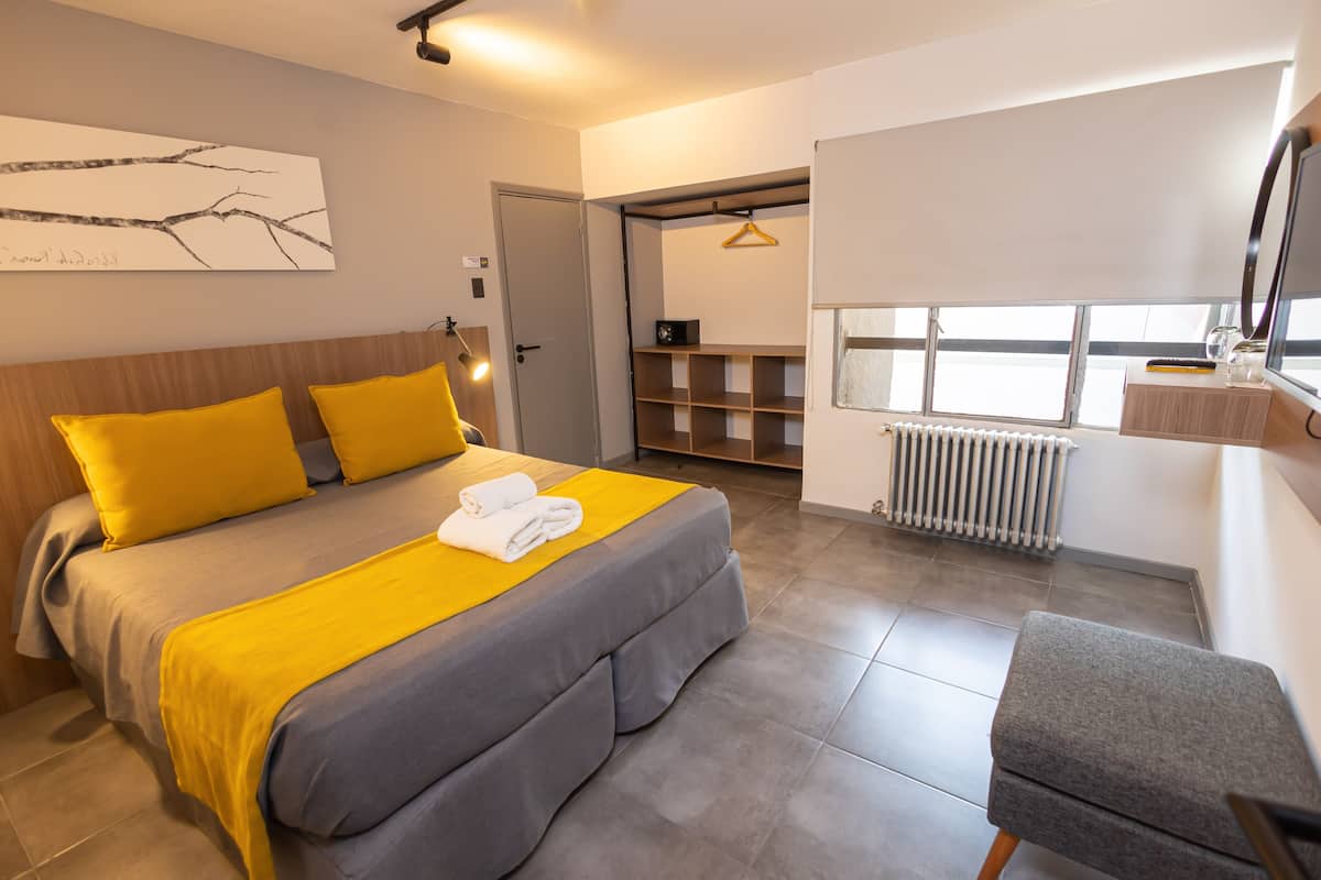 A modern bedroom with a bed, a chair, a radiator, and a window.