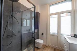 A modern bathroom with a glass-enclosed shower, a toilet, and a sink. - Amazing studio located in Ghent (Gent)