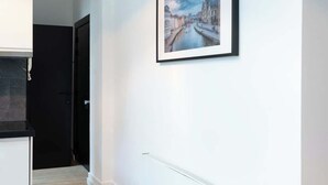 A hallway with a framed cityscape painting, a black door, and a white radiator. - Amazing studio located in Ghent (Gent)