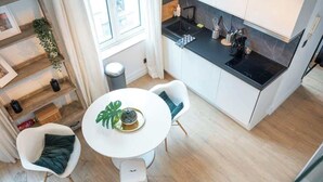 A compact kitchen with white cabinets, a black countertop, and a small dining area with a white table and two chairs. - Amazing studio located in Ghent (Gent)
