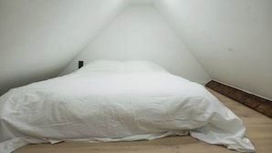 Ein kleiner, dreieckiger Dachzimmer mit einem Einzelbett und einer geneigten Decke.