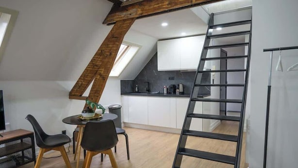 Ein Loft-Zimmer mit Essbereich, Küche und Schlafplatz in der Höhe, erreichbar über eine Leiter.